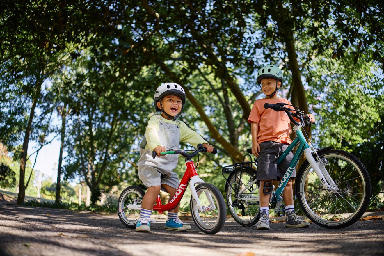 Twee kinderen fietsen op een woom GO-fiets met een READY-helm op.