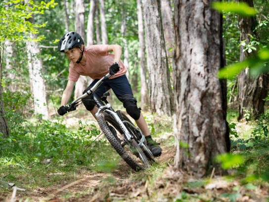 Een jongen op één van de woom mountainbikes in het bos.
